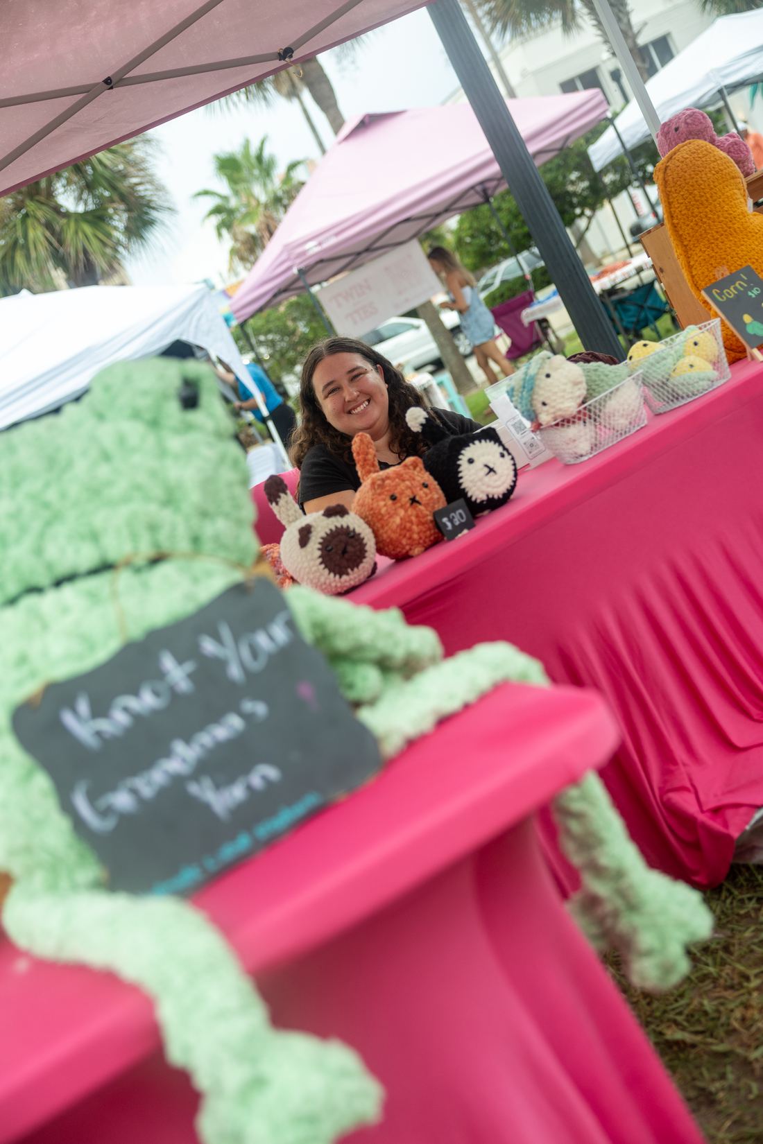 Crochet plushie vendor smiling behind her table